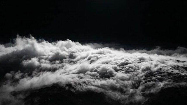 Aerial view of white clouds drifting over dark landscape at night