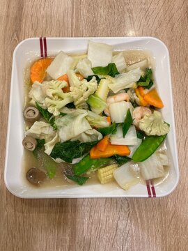 Top view of a healthy stir fried mixed vegetables dish with shrimp served on a white square plate.