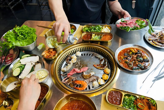 High Angle View of People Cooking Shrimp, Beef, and Vegetables on a Korean BBQ Grill