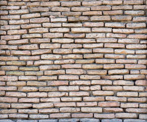 Obraz premium Texture of an old brick wall made of light brown and beige bricks. The rough surface with natural imperfections is perfect as a background for architectural and graphic design projects.