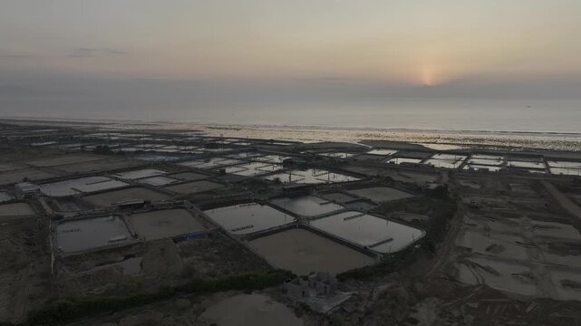 Aerial drone footage of sunrise over Phuoc Dinh shrimp farms in Khanh Hoa, Vietnam, featuring aquaculture ponds, golden reflections and sustainable seafood farming along the coastal landscape.