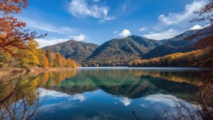 Fototapeta premium Autumn landscape with mountains, lake, and colorful trees under blue sky