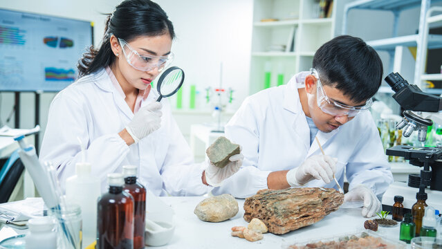 Scientist laboratory rock microscope protective eyewear research analysis sample geology experiment focused team studies mineral specimen in clean lab with magnifier glove glassware