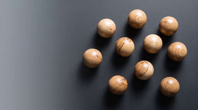 Natural wooden spheres on dark background, group of ten round timber balls with visible grain, minimalist composition of organic wood elements