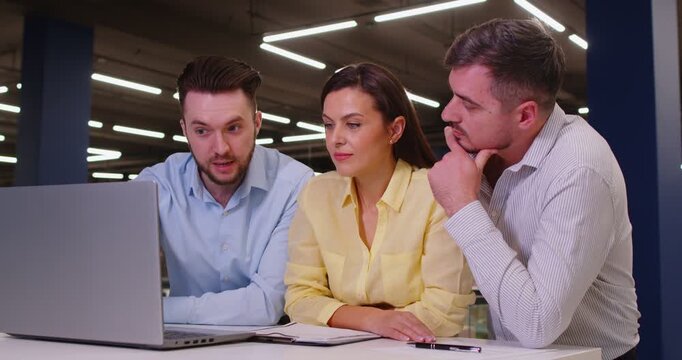 Salesman manager of construction market helping customers with choice making purchase in hypermarket standing at desk with laptop. Man seller consulting young couple in shopping mall. 4k video.