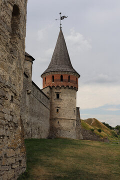 Old stone castle tower stands near grassy area with cloudy sky in the background in an unknown location
