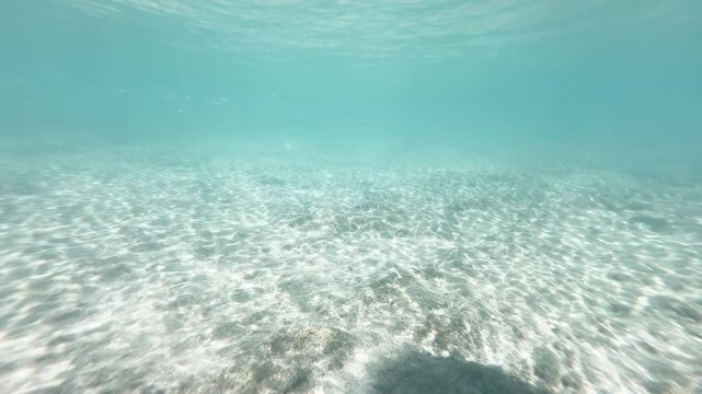 Dark shallow underwater sandy seabed with bright caustic light patterns in turquoise ocean, natural marine background, 4K_1_IMG_5264_16s_0,00.MOV.mov