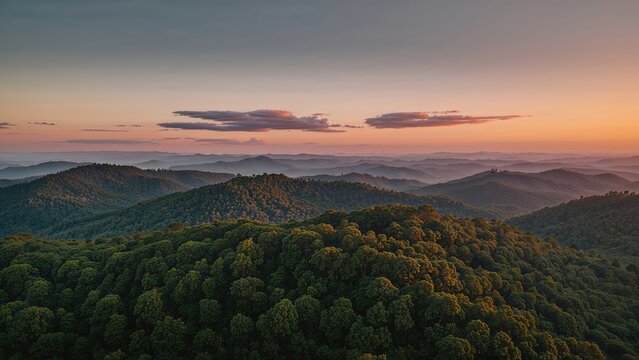 A scenic view of rolling green hills at sunset, showcasing layered mountain ranges and a colorful sky with clouds.