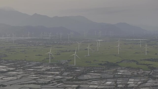 Aerial drone footage of Dam Nai Wind Farm in Khanh Hoa, Vietnam, featuring rows of wind turbines across coastal wetlands, showcasing renewable energy, sustainable power and scenic landscape.