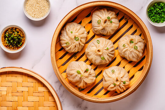 Steaming basket filled with dumplings on a marble table