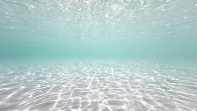 Bright shallow underwater sandy seabed with shimmering sunlight wave patterns in turquoise ocean, natural marine background, 4K_1_IMG_5271_20s_0,03.MOV.mov