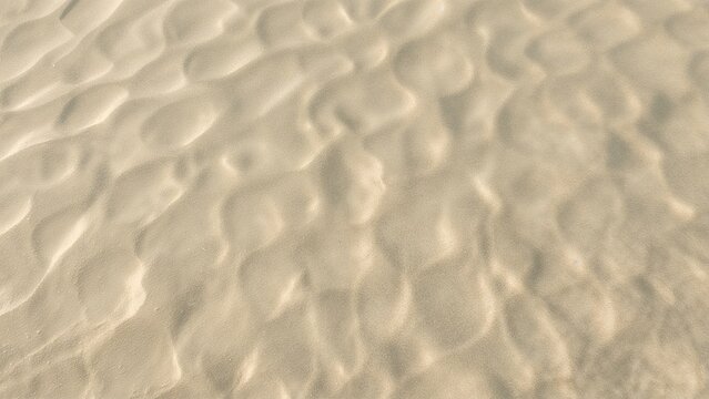 Sand dunes with textured surface. Landscape and desert environment. Natural terrain and geological formation. The scene captures the intricate patterns of the desert sand.