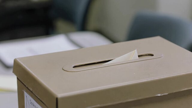 Unrecognizable male voter casting a ballot into a ballot box during an election, symbolizing the importance of civic duty, democracy, and freedom of choice