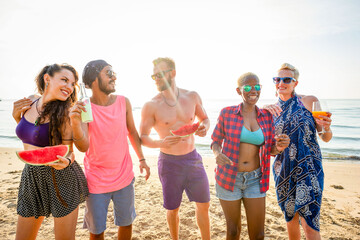 Obraz premium Group of friends enjoying watermelon and drinks on a sunny beach.