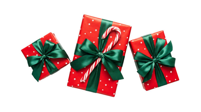 Three red christmas gift boxes with green ribbons and a candy cane isolated on a black background