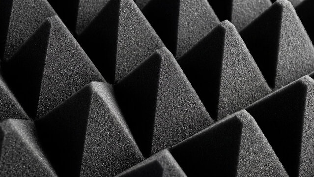 Acoustic foam panels arranged in a geometric pyramid pattern create a rhythmic texture under dramatic side lighting.