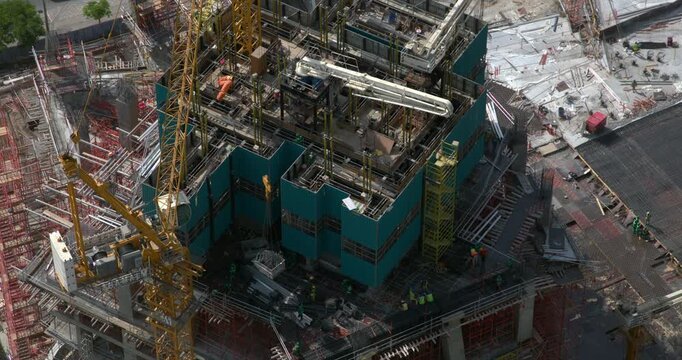 Timelapse of a yellow tower crane rotating at a high rise building construction site, its long jib swinging above the concrete structure