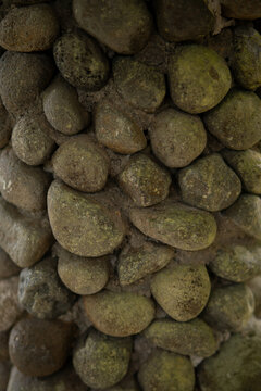 Close up detail texture of small rounded river stones bonded together on a wall surface