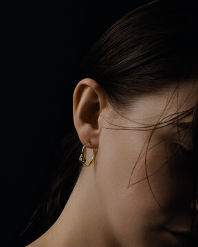 Minimal gold hoop earring on female ear close up