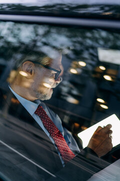 A man using a mobile phone and a tablet in the car