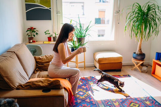 A woman drinks a hot drink sitting on the couch