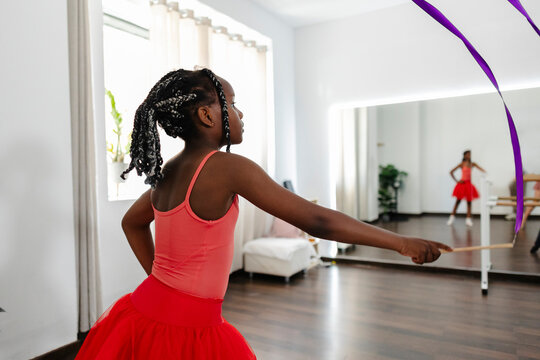 Young girl practicing rhythmic gymnastics with a purple ribbon