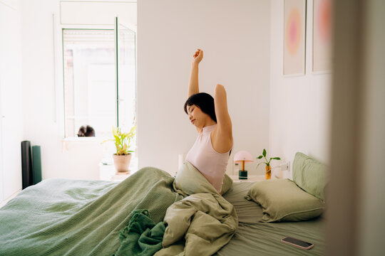 A woman stretching in bed