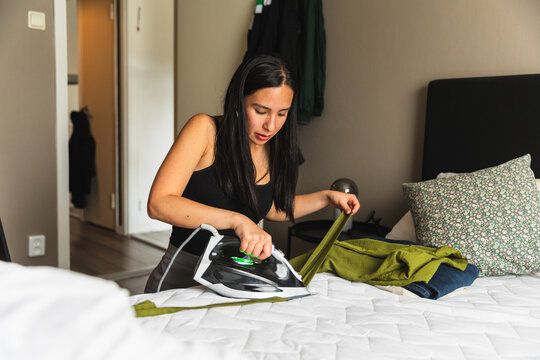 Focused Woman Care for Garment Ironing on Bed