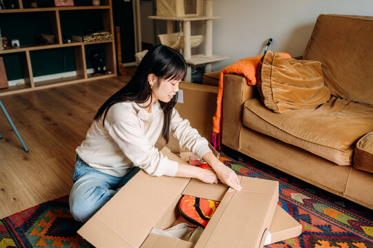 A woman opening a box sitting on the floor