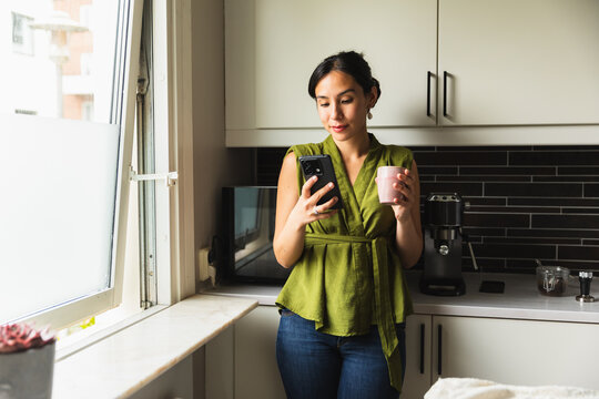 Smiling Woman with Coffee Mug Looking at Phone