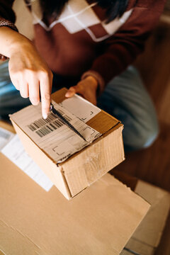 A woman opening a box sitting on the floor