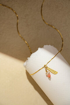 Delicate Gold Pearl Charm Necklace on White Rolled Paper