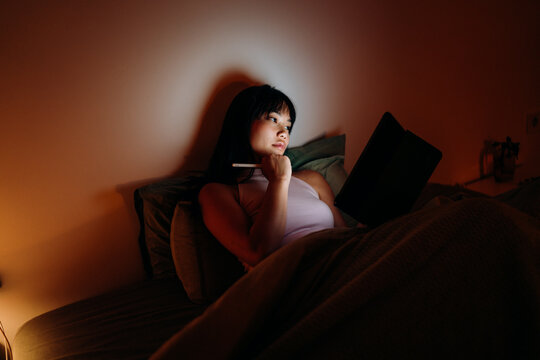 A woman uses a tablet in the bed at night
