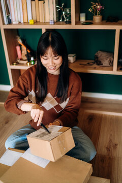 A woman opening a box sitting on the floor