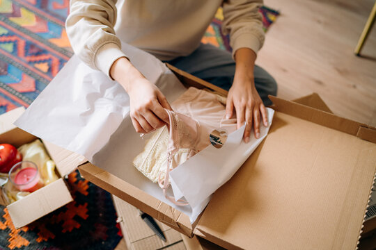 A woman opening a box sitting on the floor