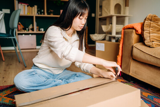 A woman opening a box sitting on the floor