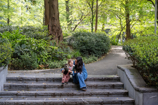 Mother Playing With Baby Girl On Park Stairway In London