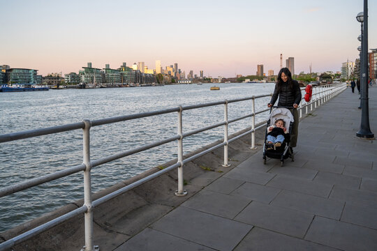 Mother Walking With Baby Girl Along Riverside Promenade In London