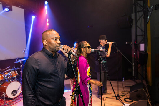 Black male vocalist singing performing with band on stage