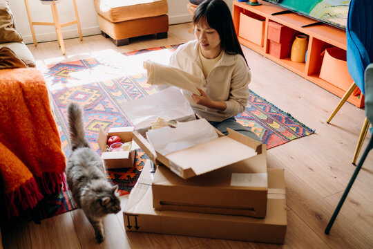 A woman opening a box sitting on the floor