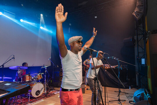 African performer raising arms singing live on stage