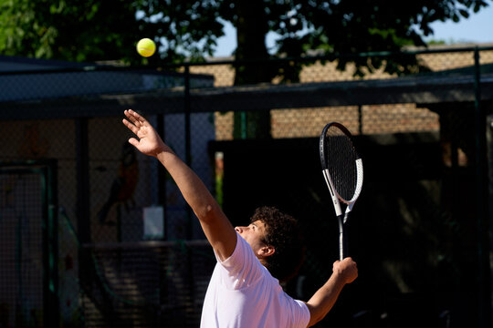 Player Serves a Tennis Ball at a Court Under Clear Sky