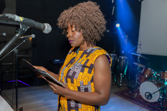 African american woman performing on stage reading script