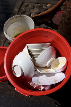 Empty Bowls and Plates Placed in a Red Bucket on the Street