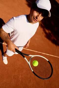Young Man Plays Tennis on a Clay Court During Sunny Weather