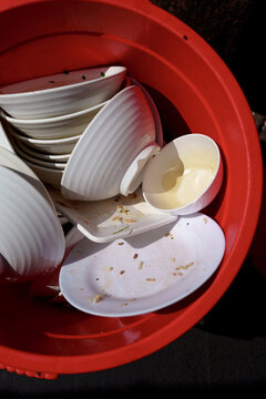 Used Plates and Bowls in a Red Bucket After a Meal