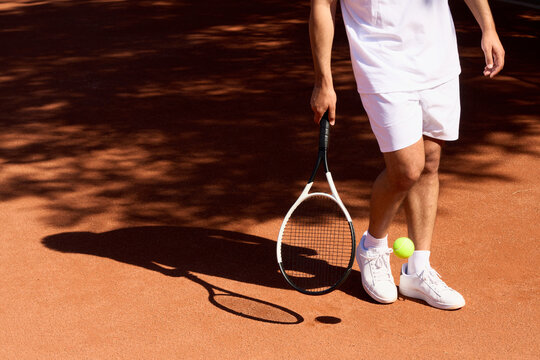 Tennis Player Prepares for a Game on a Clay Court in Bright Sunlight