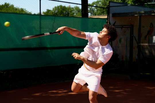 Young Player Prepares to Serve Tennis Ball on Court During Summer