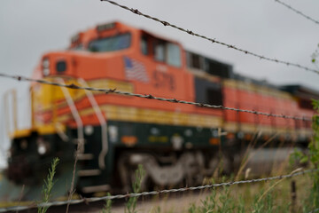 Barbed wire preventing access to retired freight locomotive awaiting further use or dismantling on an industrial site in North Texas USA, © John