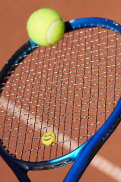 Tennis Ball and Smiley Face on a Blue Racket at a Court